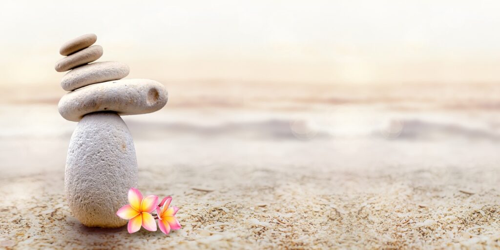 Sophrologie pour les phobies à Andernos-les-Bains – plage calme avec cailloux blancs, mer douce et petite fleur rose évoquant sérénité et apaisement.